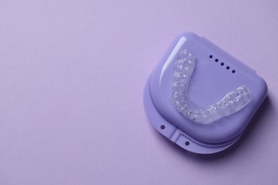 Photo of One clear aligner and retainer case on violet background, top view. Space for text