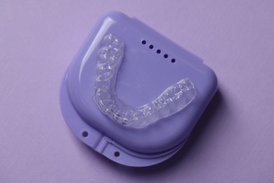 Photo of One clear aligner and retainer case on violet background, top view