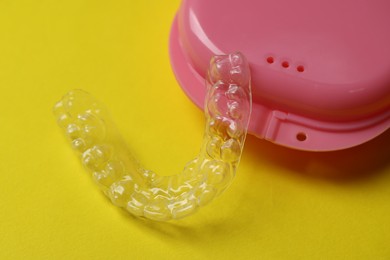 Photo of One clear aligner and retainer case on yellow background, closeup