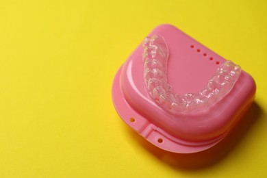 Photo of One clear aligner and retainer case on yellow background, closeup. Space for text