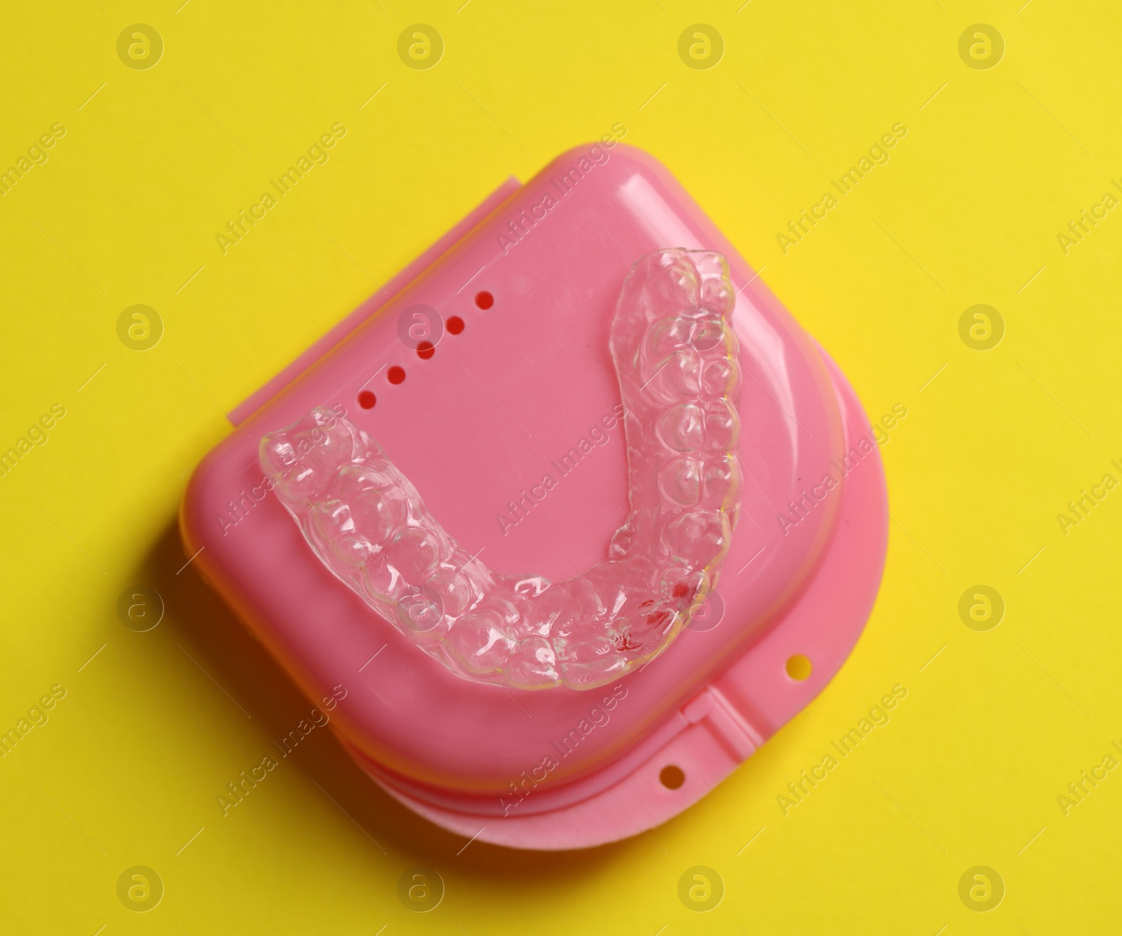 One clear aligner and retainer case on yellow background, top view Photo of One clear aligner and retainer case on yellow background, top view