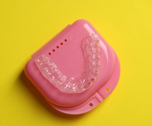 Photo of One clear aligner and retainer case on yellow background, top view