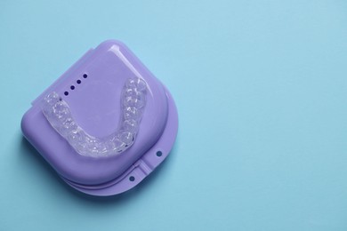 Photo of One clear aligner and retainer case on light blue background, top view. Space for text