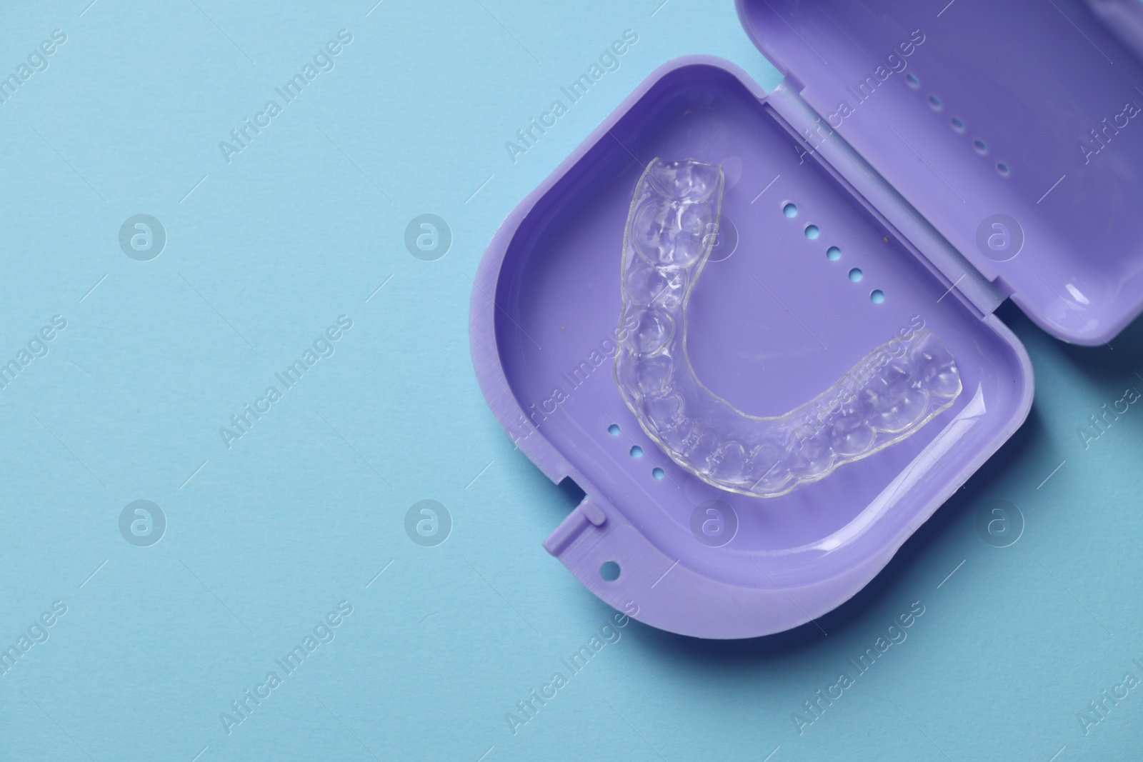 One clear aligner in retainer case on light blue background, top view. Space for text Photo of One clear aligner in retainer case on light blue background, top view. Space for text