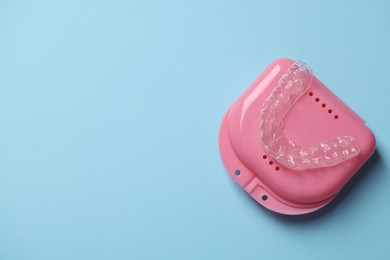Photo of One clear aligner and retainer case on light blue background, top view. Space for text