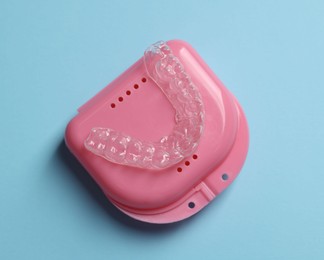 Photo of One clear aligner and retainer case on light blue background, top view
