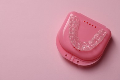 Photo of One clear aligner and retainer case on pink background, top view. Space for text