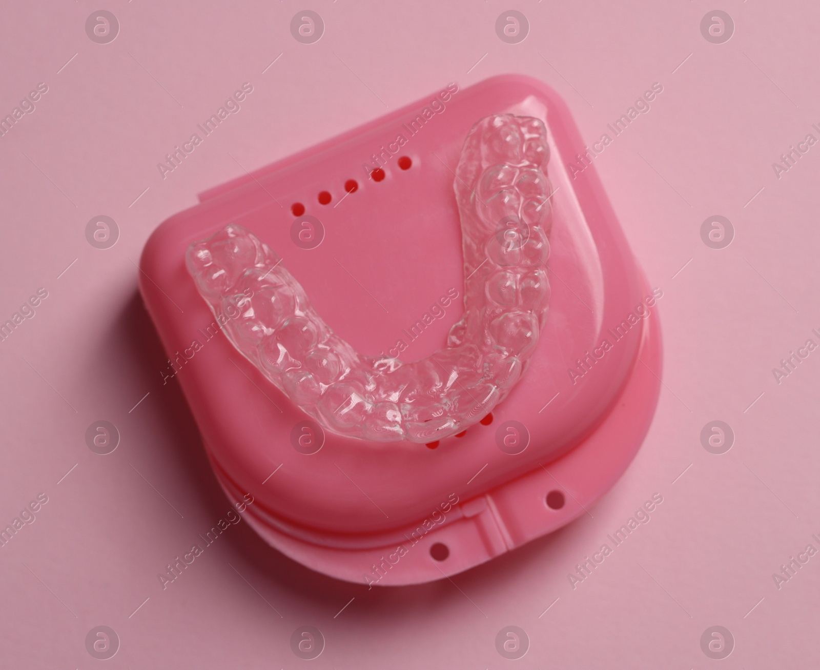 One clear aligner and retainer case on pink background, top view Photo of One clear aligner and retainer case on pink background, top view