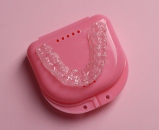 Photo of One clear aligner and retainer case on pink background, top view