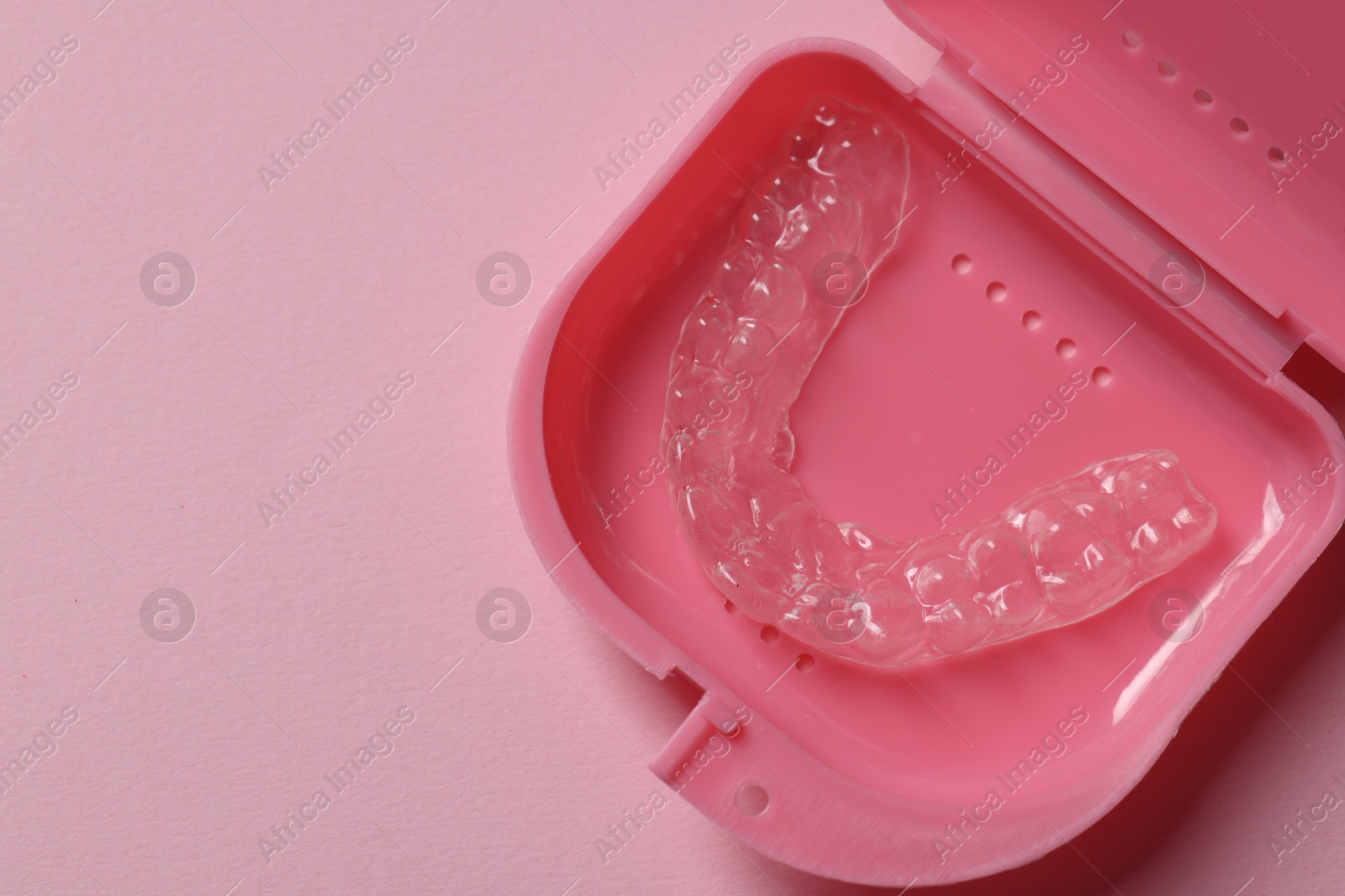 One clear aligner in retainer case on pink background, top view. Space for text Photo of One clear aligner in retainer case on pink background, top view. Space for text