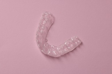 Photo of One clear aligner on pink background, top view