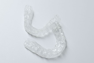 Photo of Clear aligners on light grey background, closeup