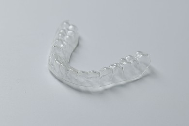 Photo of One clear aligner on grey background, closeup