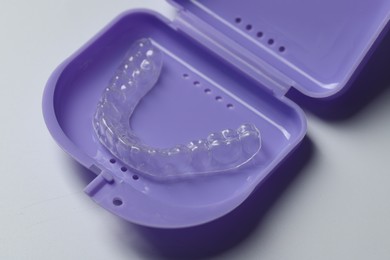 Photo of One clear aligner and retainer case on light grey background, closeup