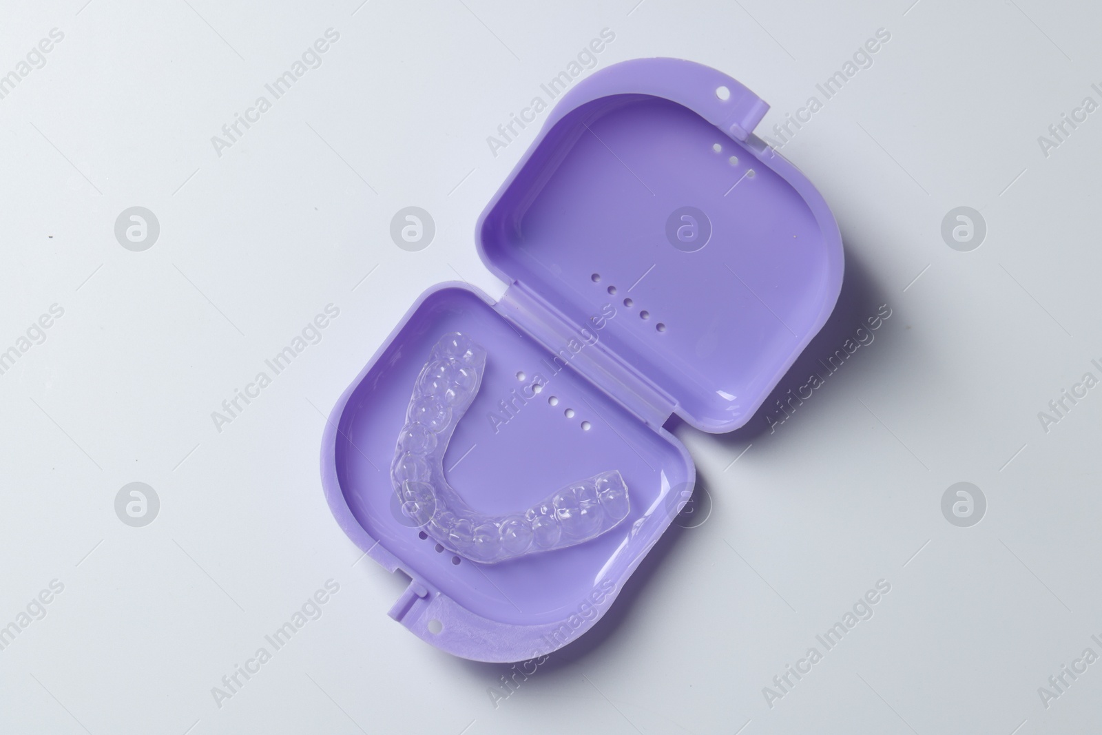 One clear aligner in retainer case on light grey background, top view Photo of One clear aligner in retainer case on light grey background, top view