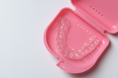 Photo of One clear aligner and retainer case on light grey background, top view. Space for text