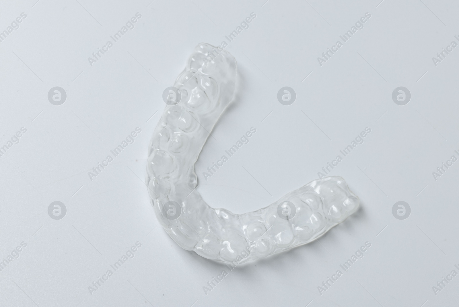 One clear aligner on light grey background, top view Photo of One clear aligner on light grey background, top view