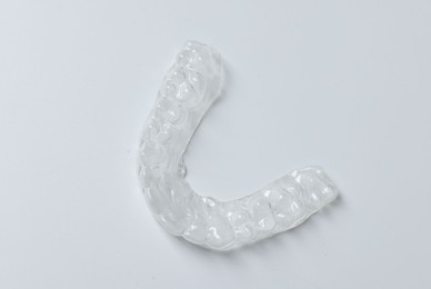 Photo of One clear aligner on light grey background, top view