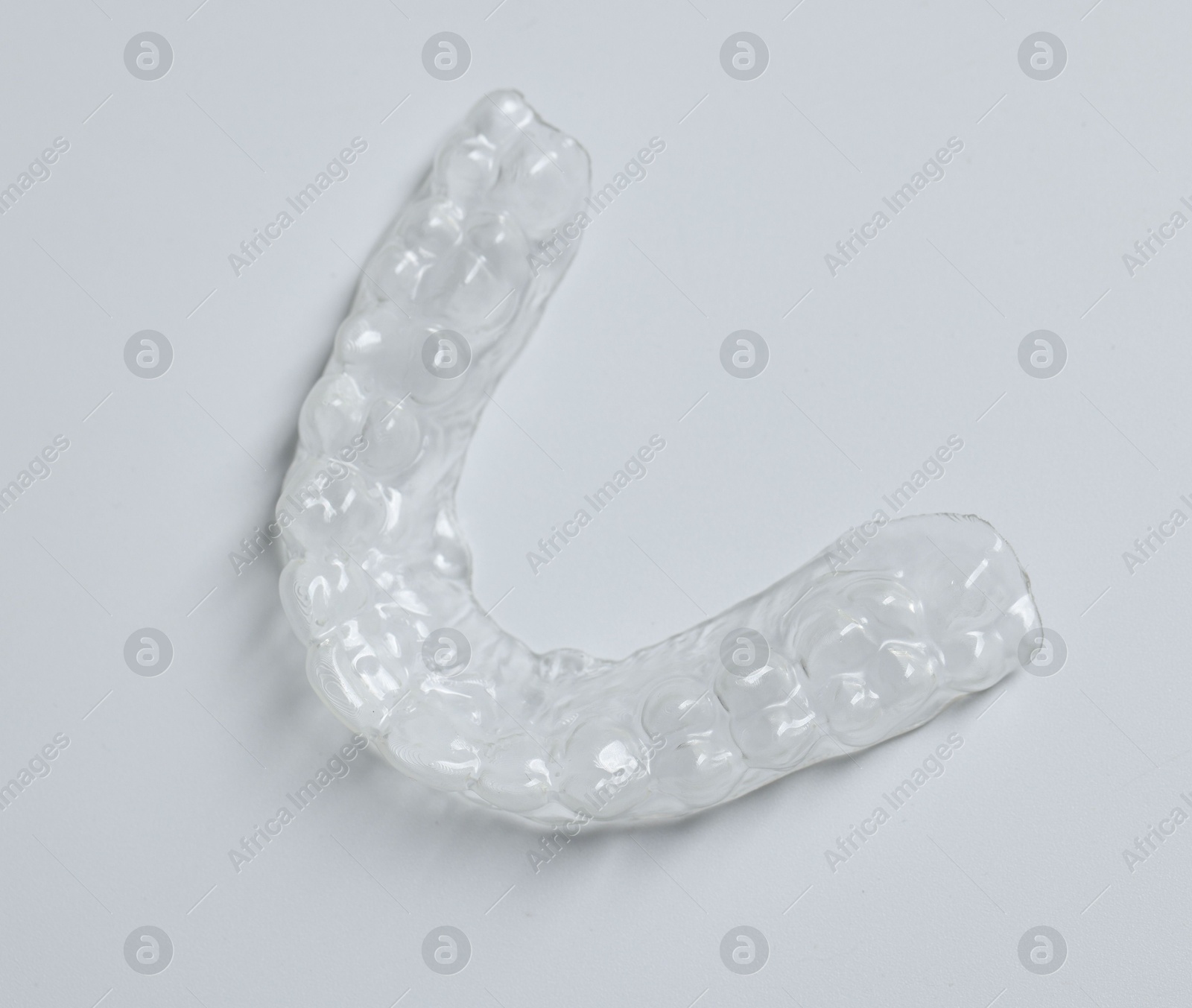 One clear aligner on light grey background, above view Photo of One clear aligner on light grey background, above view