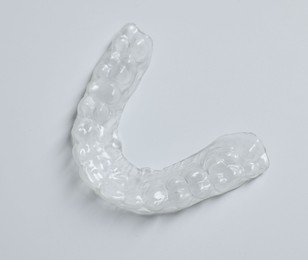 Photo of One clear aligner on light grey background, above view