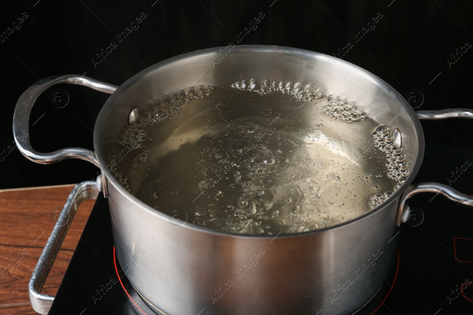 Metal pot with boiling water on stove in kitchen, closeup Photo of Metal pot with boiling water on stove in kitchen, closeup