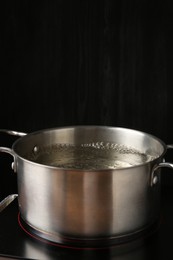 Photo of Metal pot with boiling water on stove in kitchen, space for text