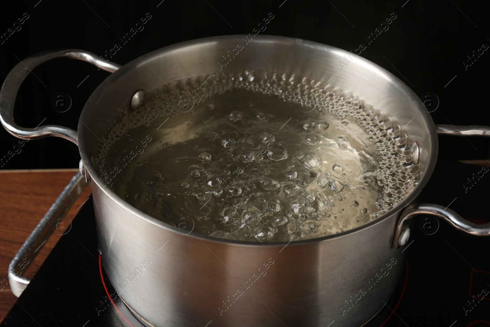 Metal pot with boiling water on stove in kitchen, closeup Photo of Metal pot with boiling water on stove in kitchen, closeup