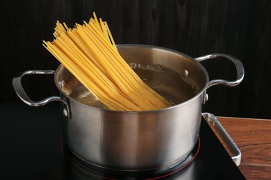 Photo of Fresh tagliatelle pasta boiling in pot with water on electric stove, closeup