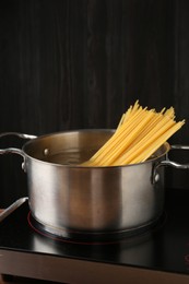 Photo of Fresh tagliatelle pasta boiling in pot with water on electric stove, closeup