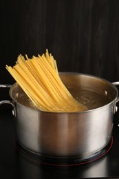 Photo of Fresh tagliatelle pasta boiling in pot with water on electric stove, closeup