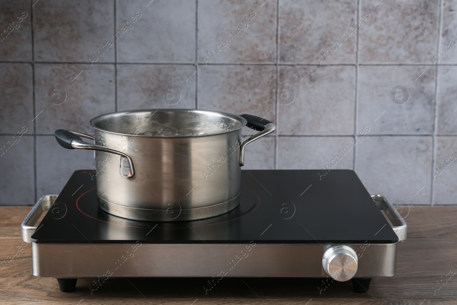 Metal pot with boiling water on stove in kitchen Photo of Metal pot with boiling water on stove in kitchen