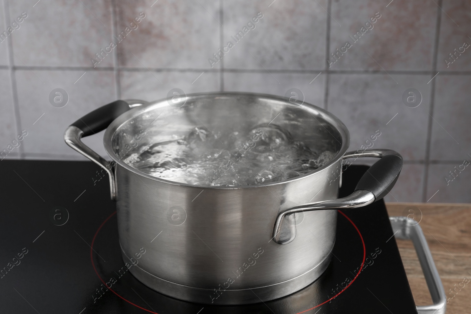 Metal pot with boiling water on stove in kitchen, closeup Photo of Metal pot with boiling water on stove in kitchen, closeup