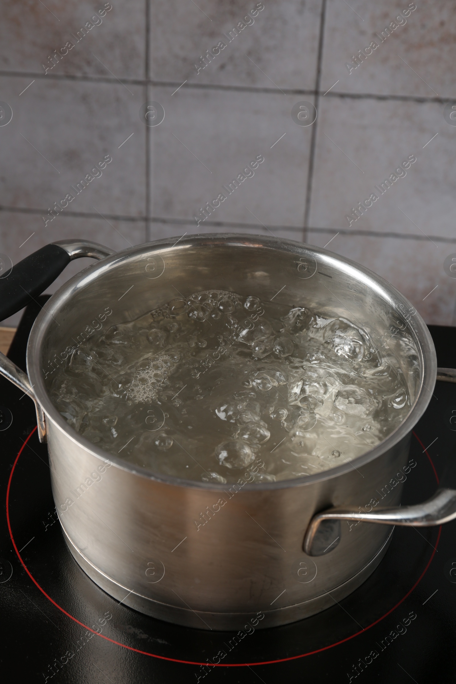 Metal pot with boiling water on stove in kitchen, closeup Photo of Metal pot with boiling water on stove in kitchen, closeup