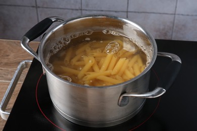Photo of Fresh pasta boiling in pot with water on electric stove, closeup