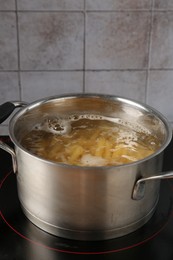 Photo of Fresh pasta boiling in pot with water on electric stove, closeup