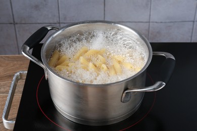 Photo of Fresh pasta boiling in pot with water on electric stove, closeup