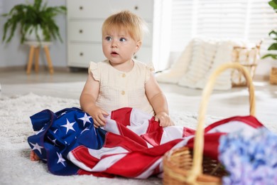 Photo of Cute little child with flag of USA and wicker basket of hydrangea flowers on floor at home