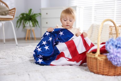Photo of Cute little child with flag of USA and wicker basket of hydrangea flowers on floor at home