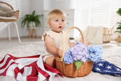 Photo of Cute little child with flag of USA and wicker basket of hydrangea flowers on floor at home