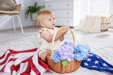 Photo of Cute little child with flag of USA and wicker basket of hydrangea flowers on floor at home