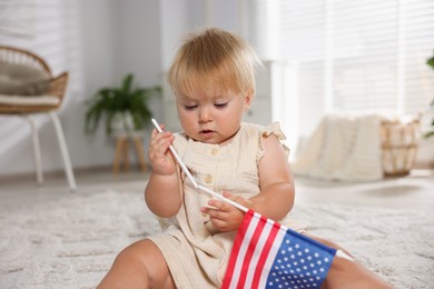 Photo of Cute little child with flag of USA on floor at home