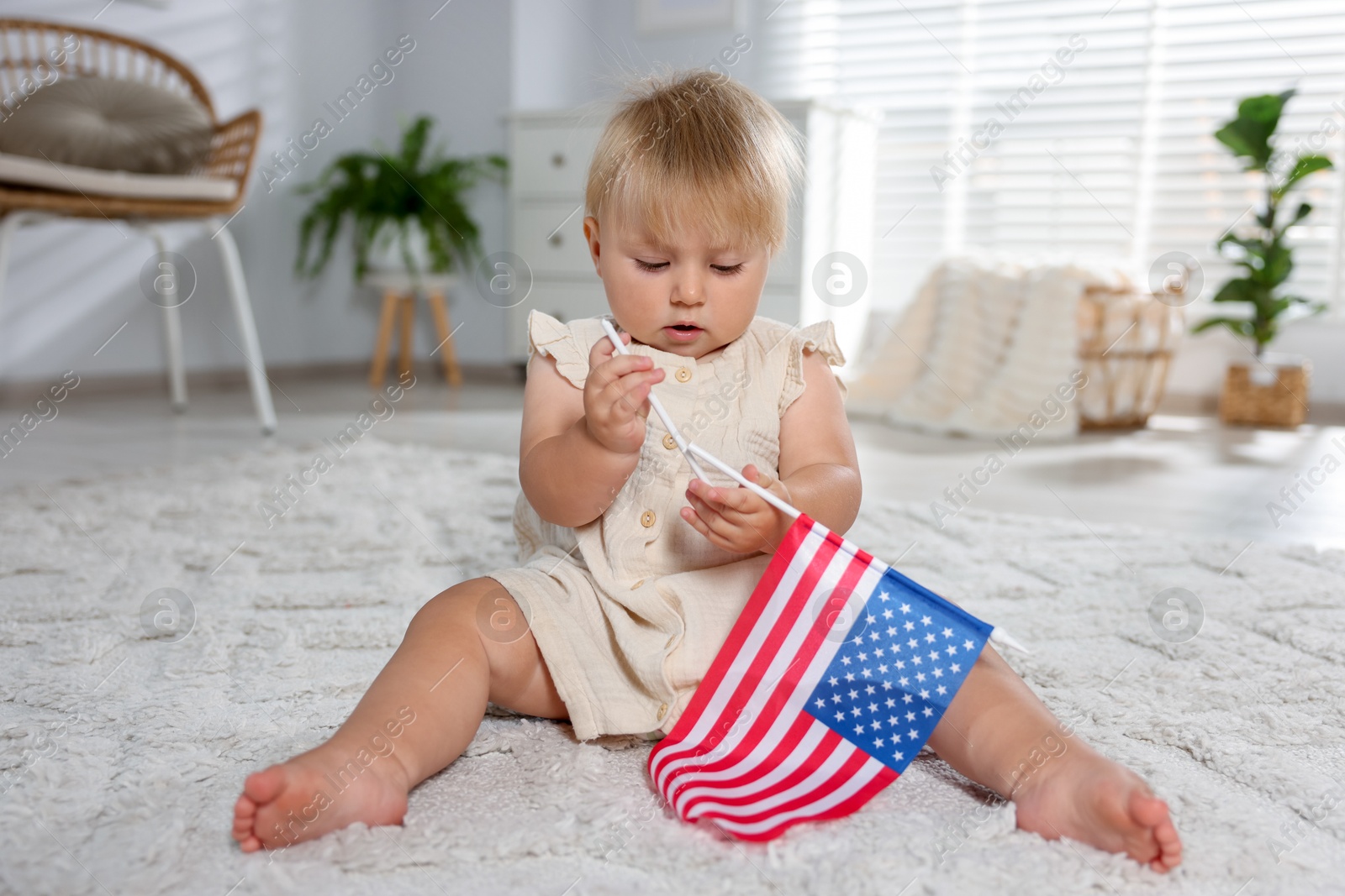 Photo of Cute little child with flag of USA on floor at home