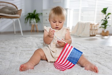 Photo of Cute little child with flag of USA on floor at home