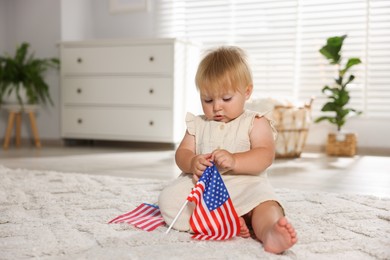 Photo of Cute little child with flag of USA on floor at home, space for text
