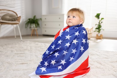 Photo of Cute little child with flag of USA on floor at home, space for text