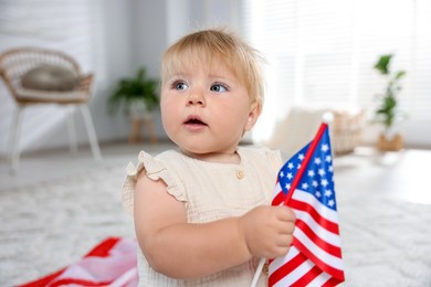 Photo of Cute little child with flag of USA on floor at home