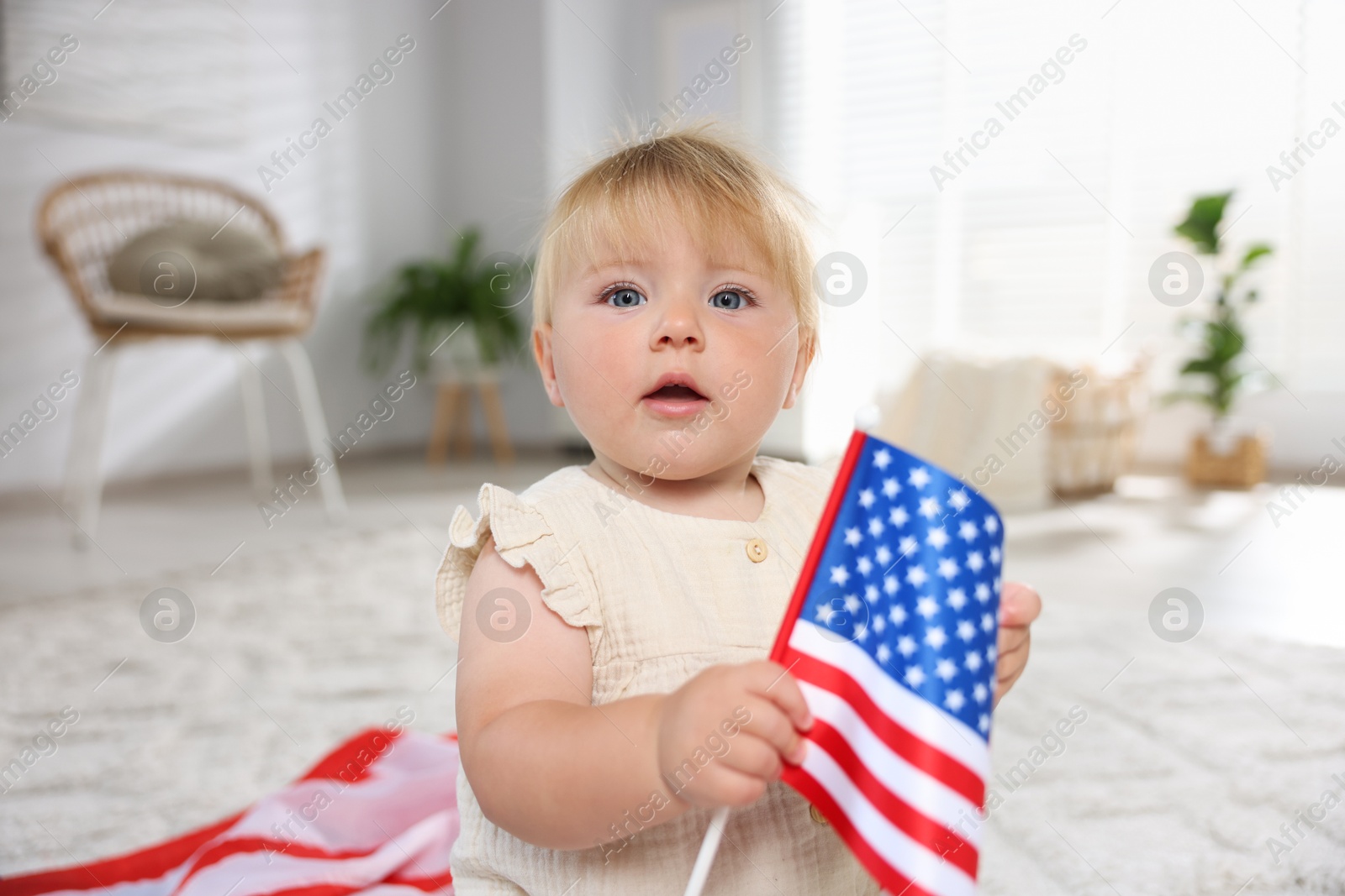 Photo of Cute little child with flag of USA on floor at home