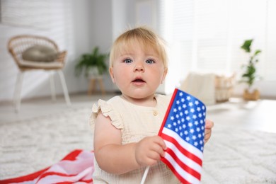 Photo of Cute little child with flag of USA on floor at home