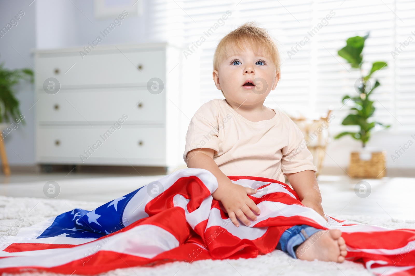 Photo of Cute little child with flag of USA on floor at home, space for text