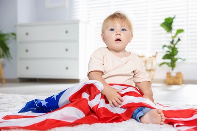Photo of Cute little child with flag of USA on floor at home, space for text